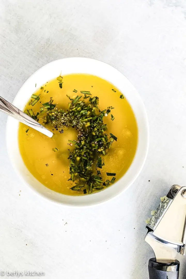 Top down view of melted butter and herbs in a pan.