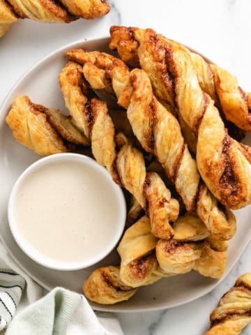 Top down view of cinnamon sticks on a plate with frosting.
