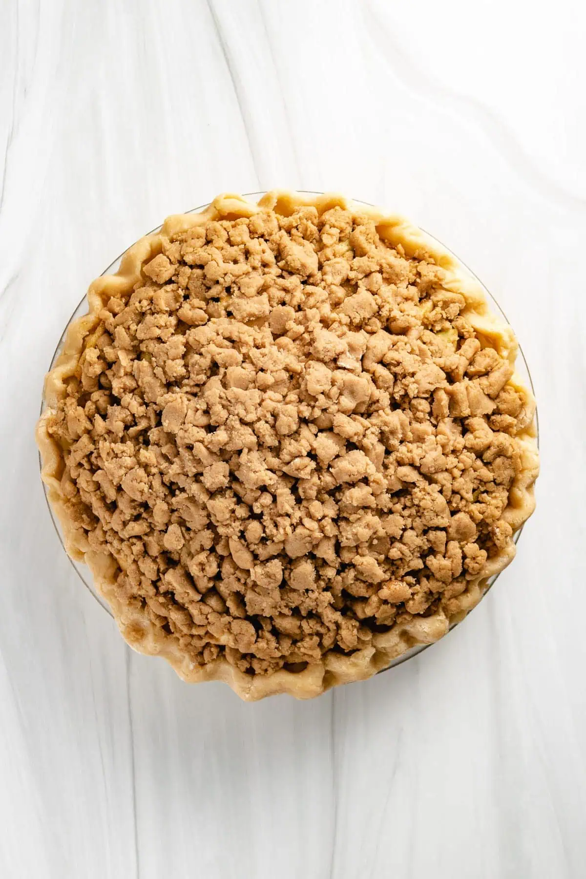 Top down view of unbaked apple pie with crumb topping.