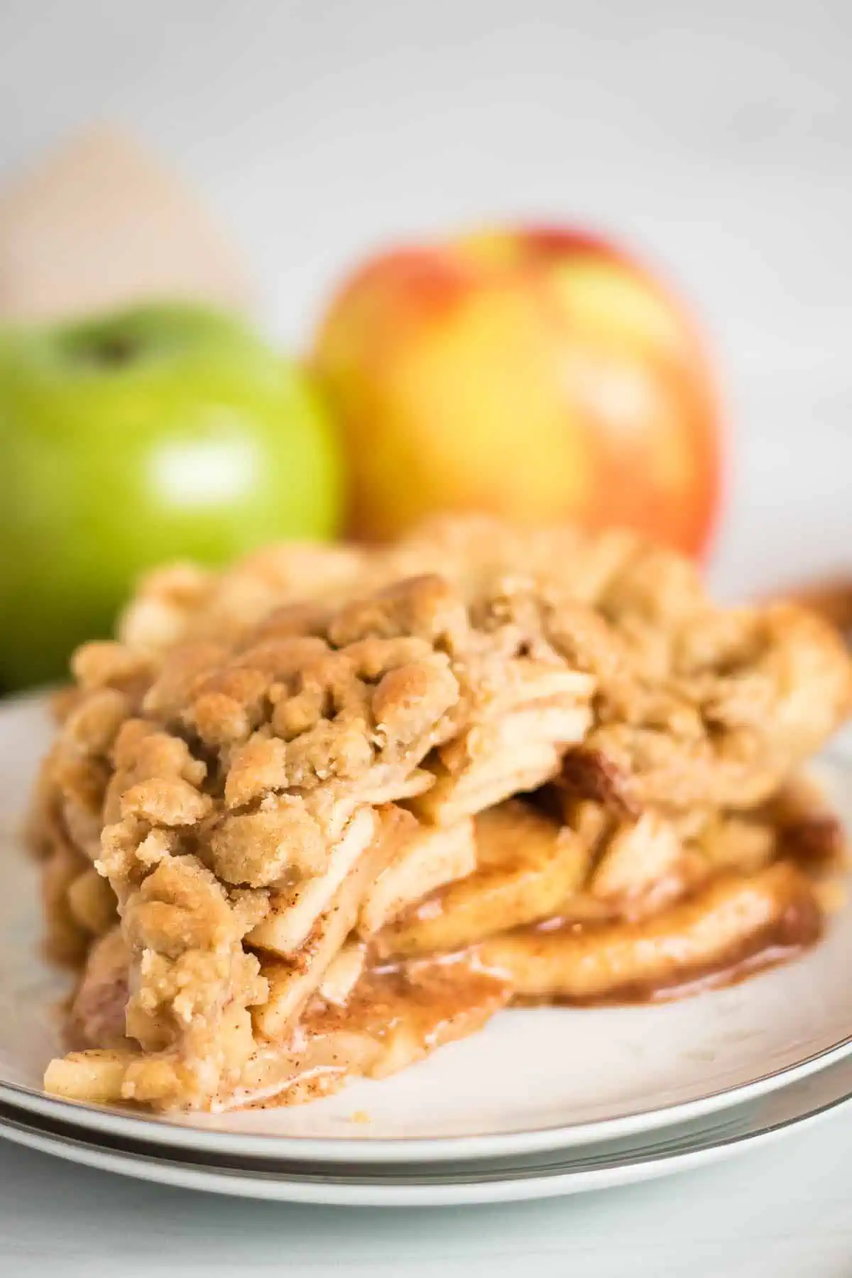 Apple pie with crumb topping on a white plate.