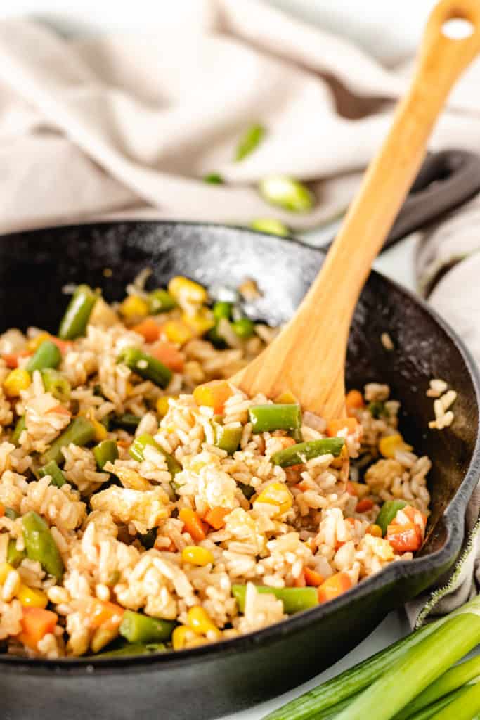 Fried rice being scooped out of a cast iron pan.