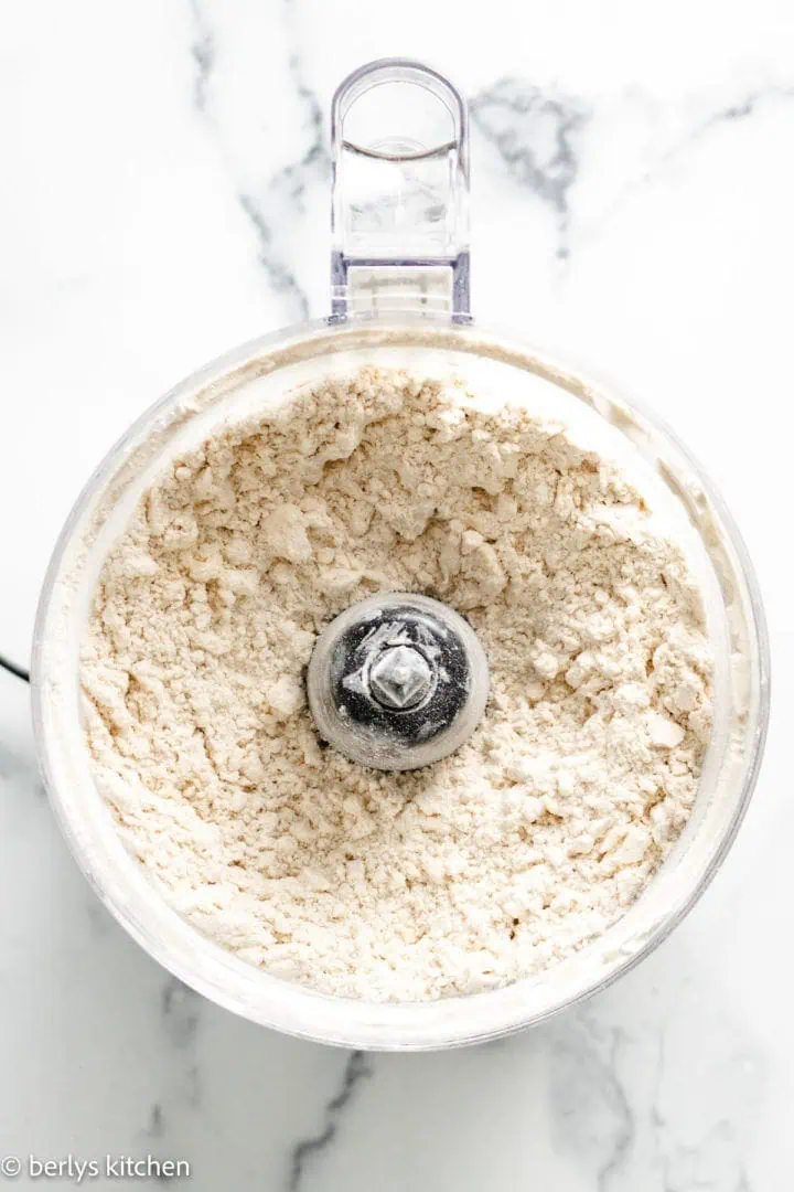 Top down view of flour mixed with butter in a food processor.