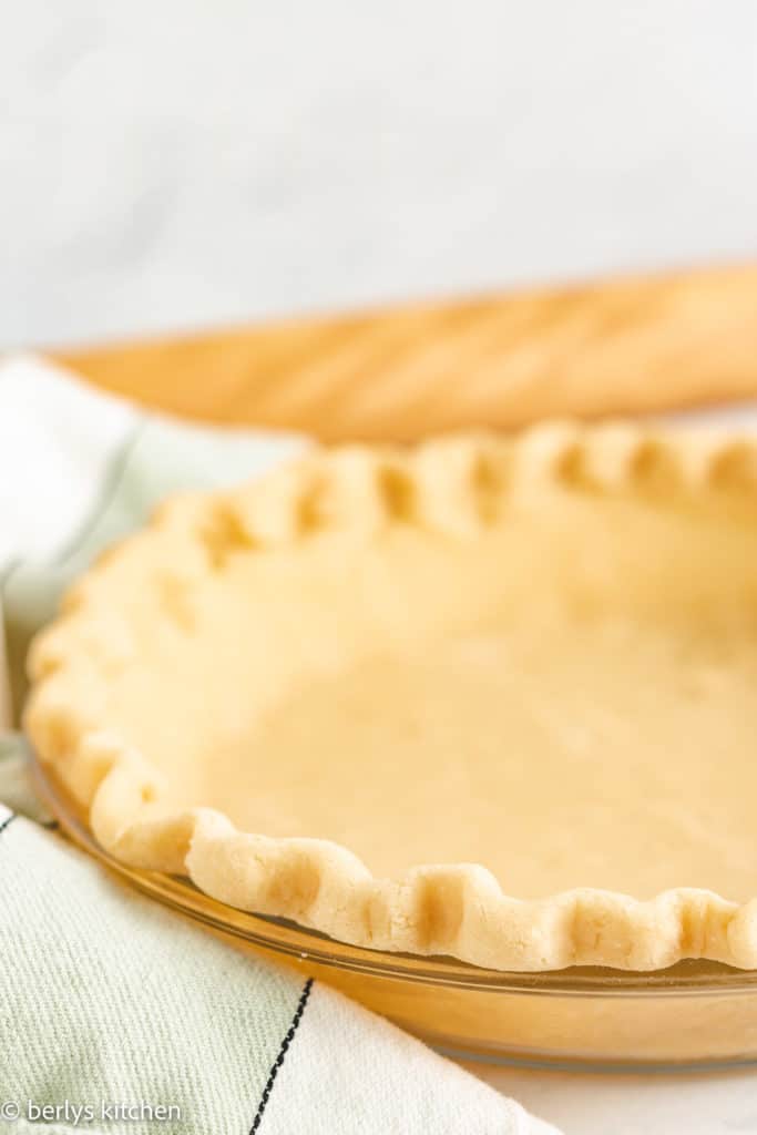 Pie crust with butter in a glass pie dish.