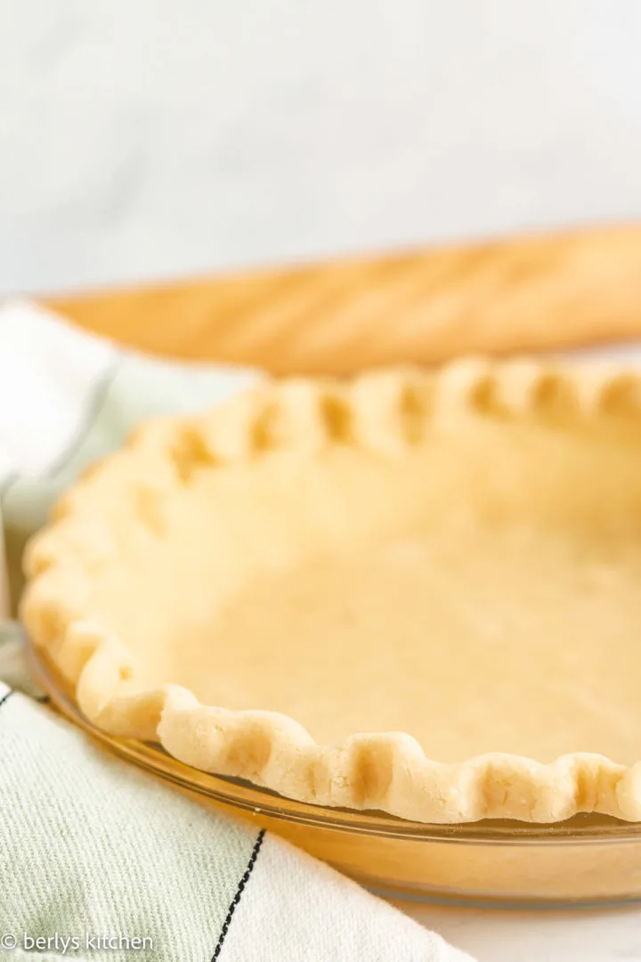 Pie crust with butter in a glass pie dish.