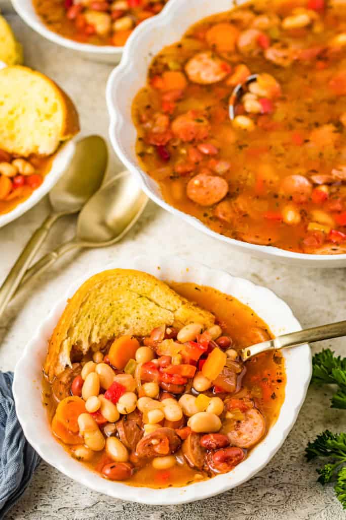 Top down view of sausage and bean soup with bread.