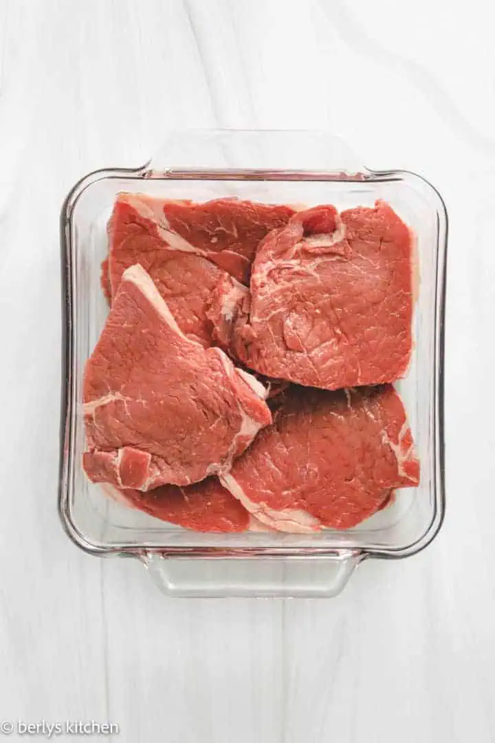Several pieces of Sirloin Steak in a pan.