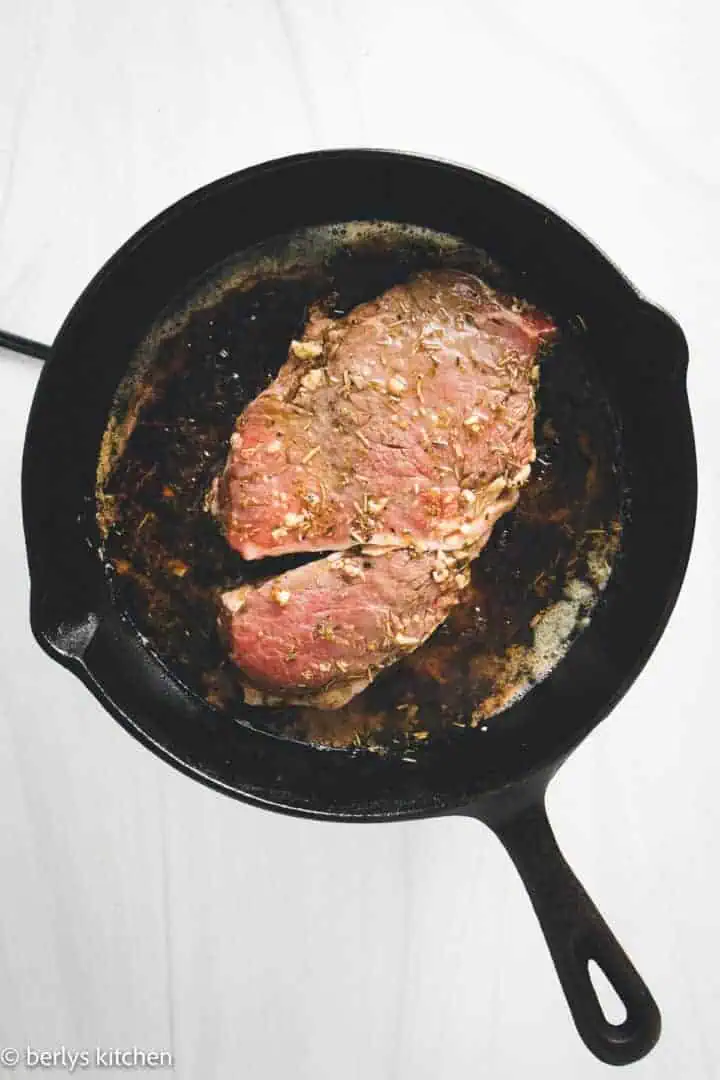 Steak cooking in a cast iron pan.