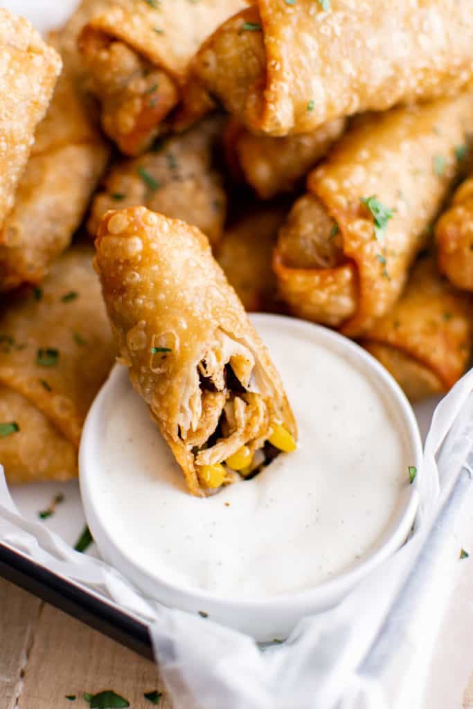 Egg roll with a bowl of dipping sauce.