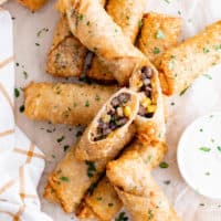 Top down view of several egg rolls and dipping sauce.