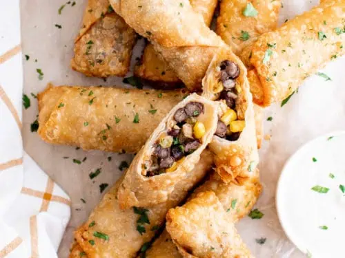 Top down view of several egg rolls and dipping sauce.