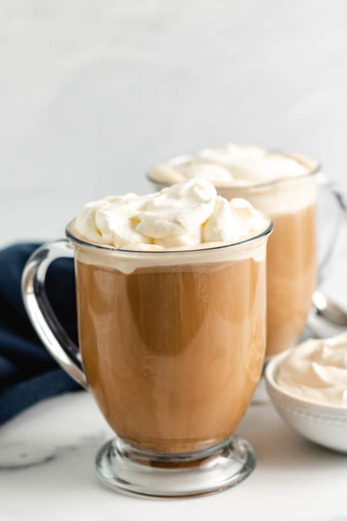 Two mugs of boozy coffee with whipped cream.