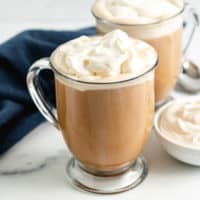 Two coffee mugs filled with amaretto coffee and whipped cream.
