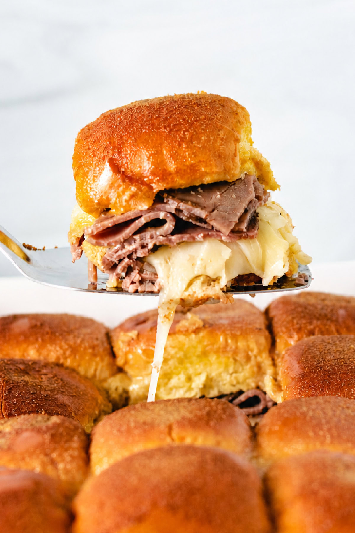 French dip slider being lifted out of a pan.