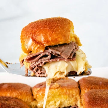Two sliders on a plate with au jus.