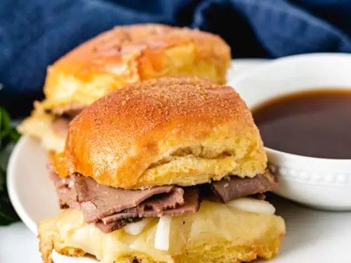 Two sliders on a plate with au jus.