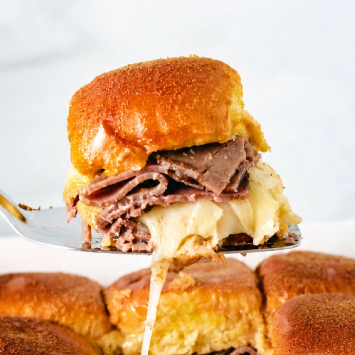 Two sliders on a plate with au jus.