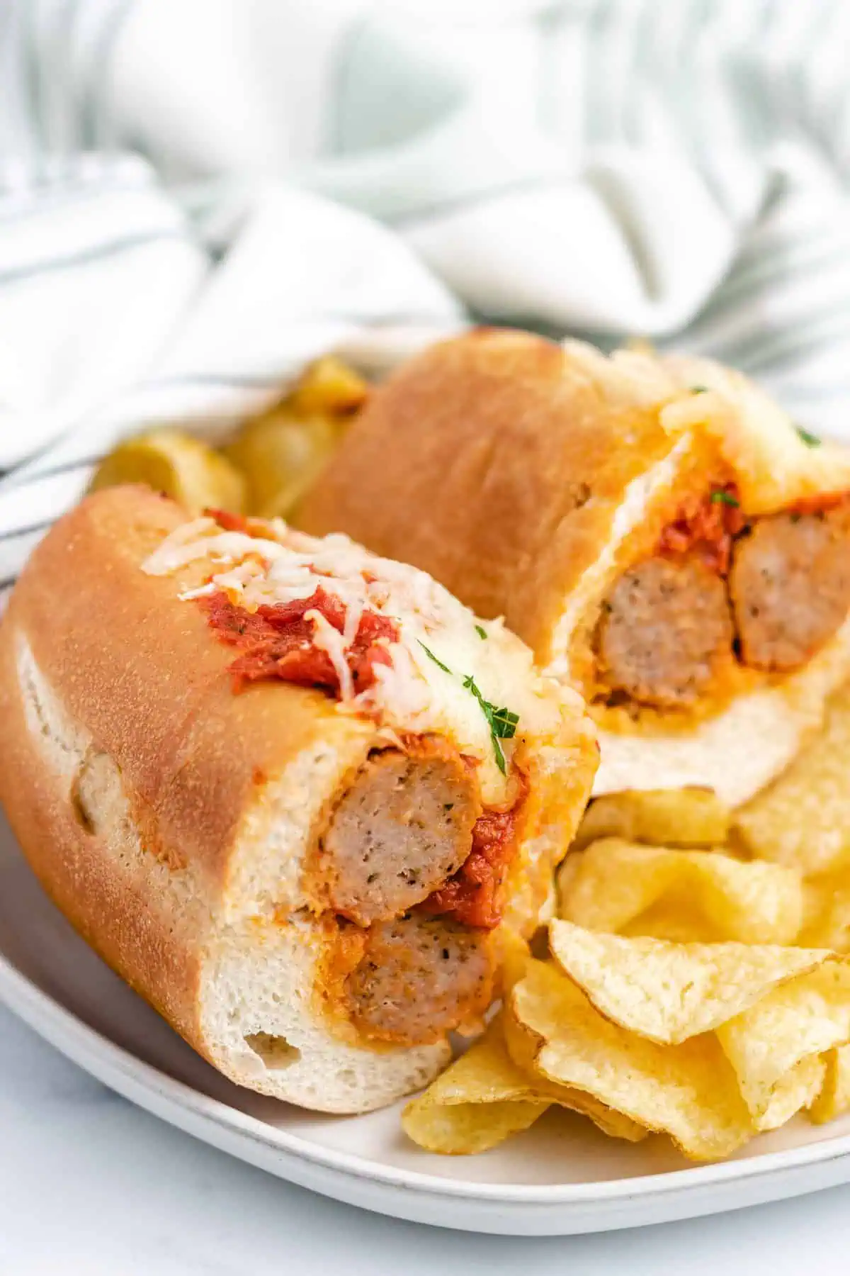 Meatball sandwich cut in half with chips.