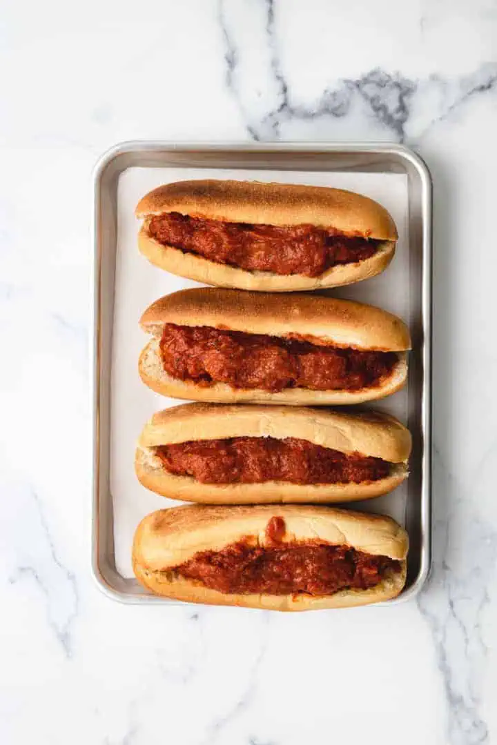 Top down view of meatballs and marinara in hoagie buns.
