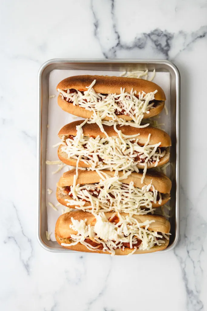 Top down view of meatball subs with shredded cheese.