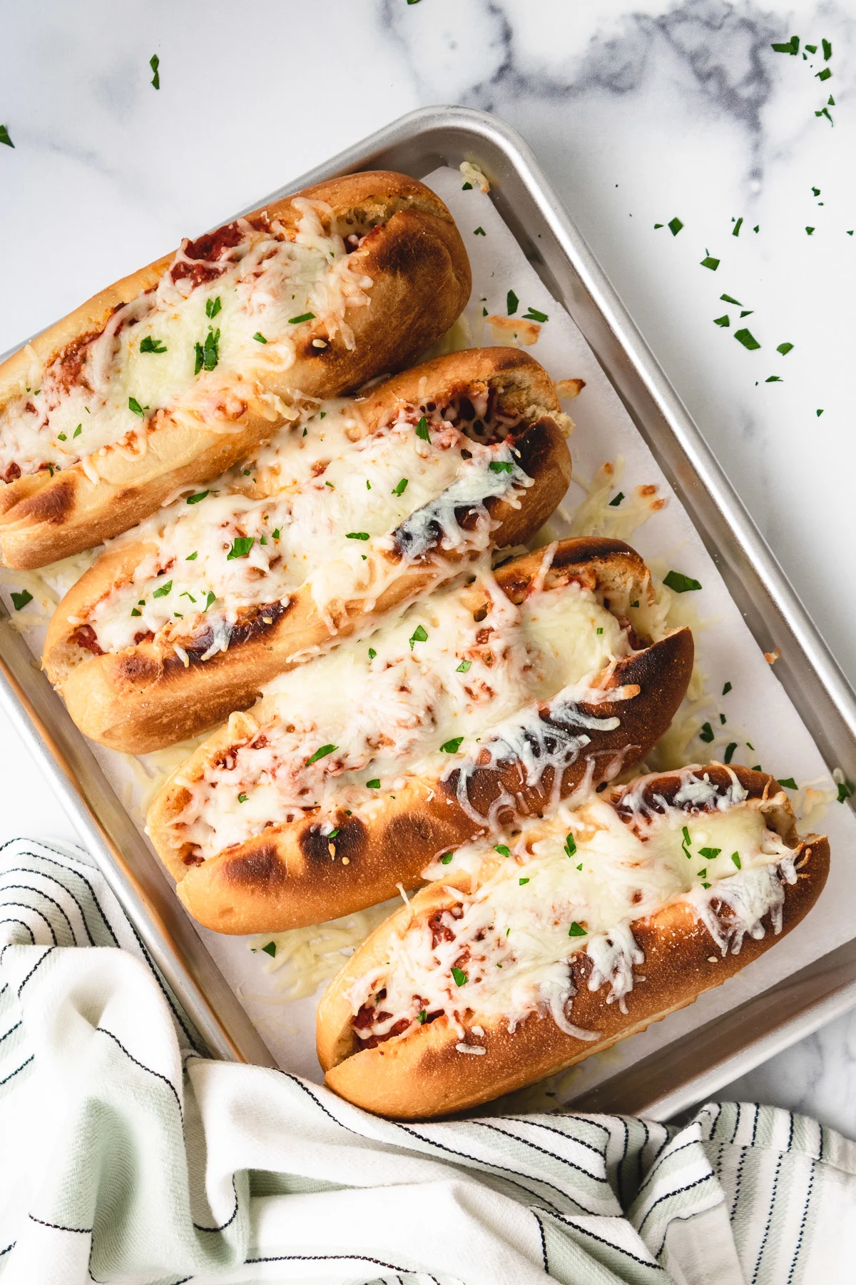 Top down view of four meatball sandwiches on a pan.
