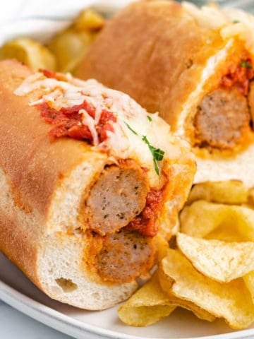 Meatball sandwich cut in half on a gray plate with chips.