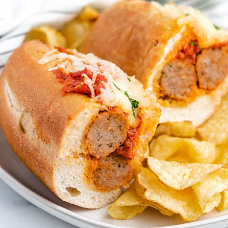 Meatball sandwich cut in half on a gray plate with chips.