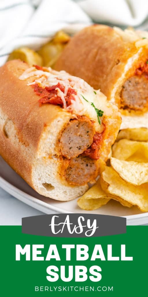 Meatball sub cut in half on a plate with chips.