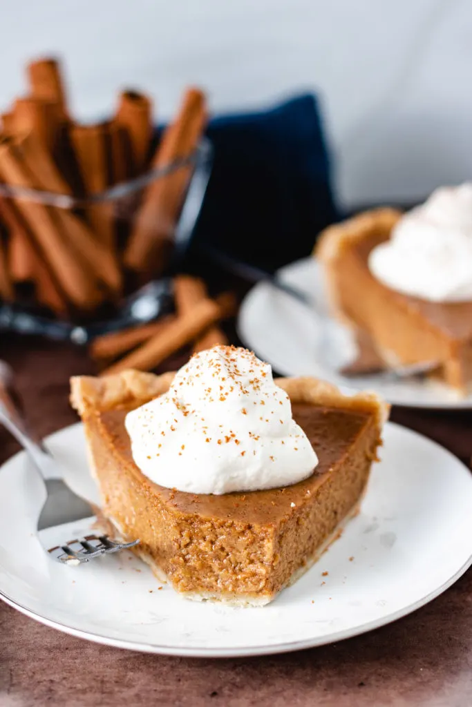 Pumpkin pie on a plate with a bite taken out.