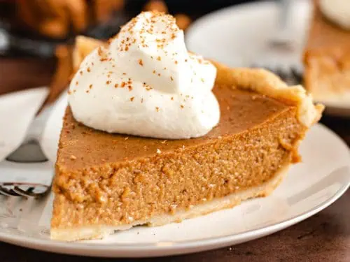 Pie with whipped cream and sprinkled cinnamon.