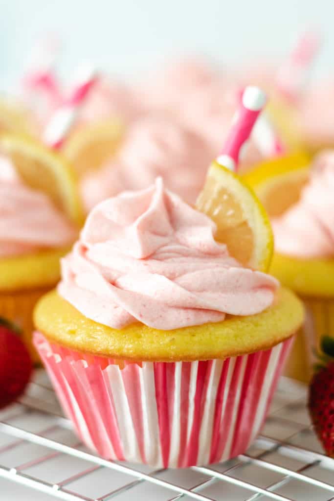 Lemonade cupcake topped with strawberry frosting and a straw.