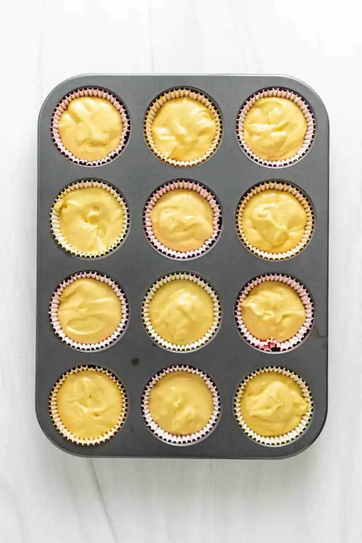 Top down view of unbaked cupcake batter in a muffin pan.