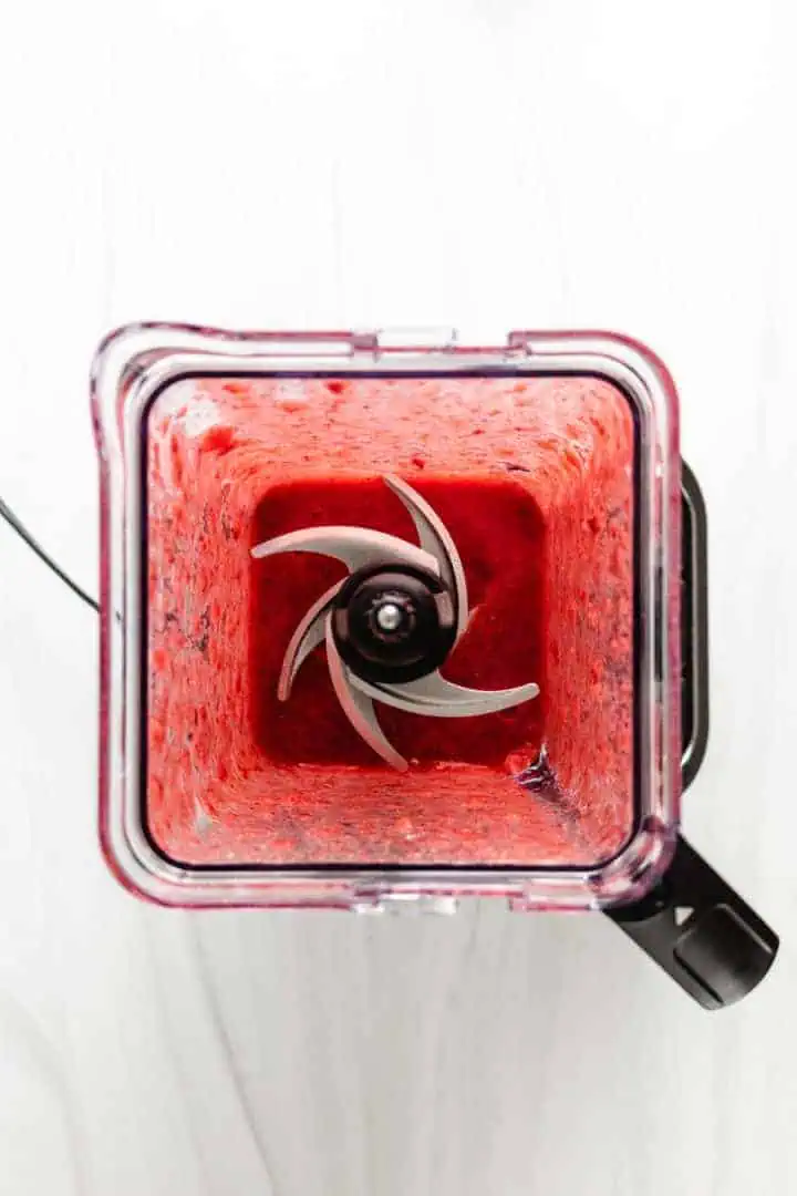 Top down view of pureed strawberries in a blender.