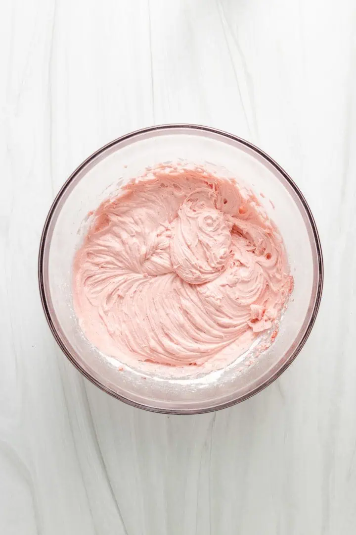 Top down view of strawberry frosting in a bowl.