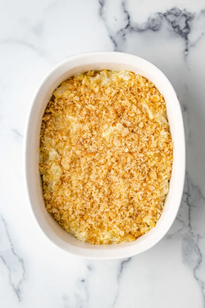 Top down view of a baking dish filled with squash casserole and crushed crackers.