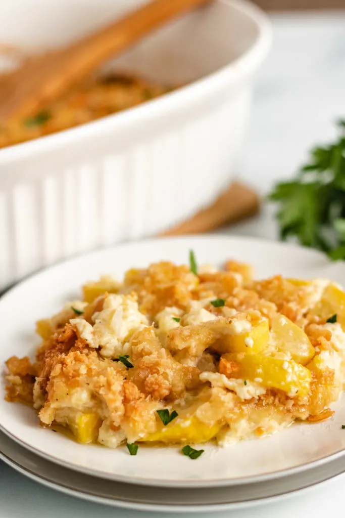 Yellow squash casserole on a white serving plate.