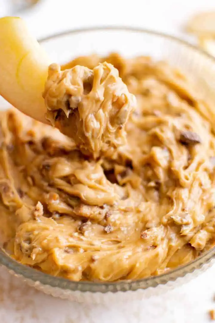 Apple slice scooping caramel dip.