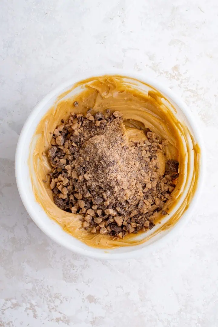 Top down view of toffee bits being added to caramel dip.