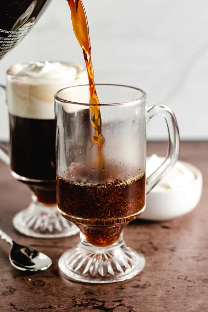 Freshly brewed coffee being poured into a glass mug.