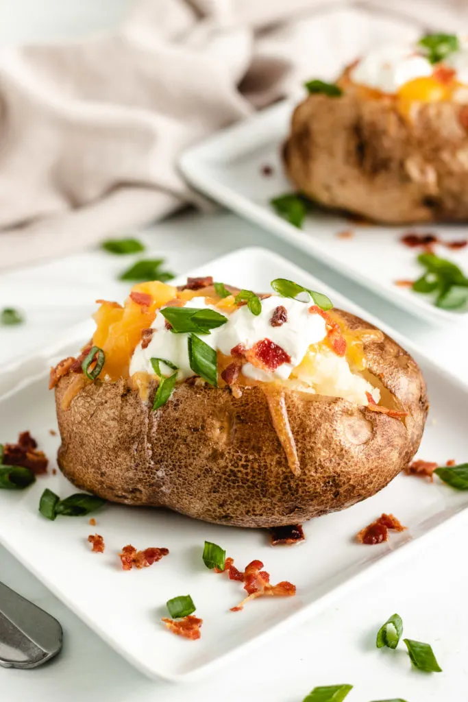 Loaded baked potato on a white plate.