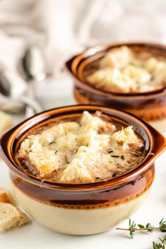 French onion soup in brown crock bowls.