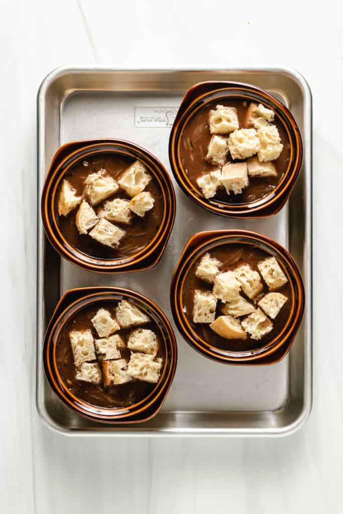 Top down view of 4 bowls of soup topped with cubed bread.