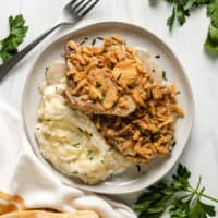 Top down view of two baked pork chops on a plate.