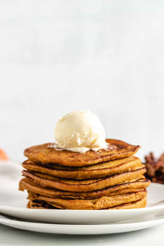 Tall stack of pumpkin pancakes with a scoop of butter. 