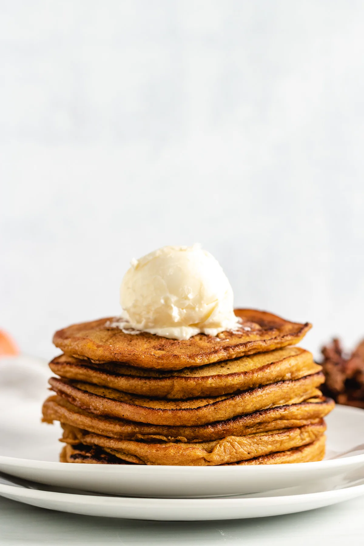 Tall stack of pumpkin pancakes with a scoop of butter.