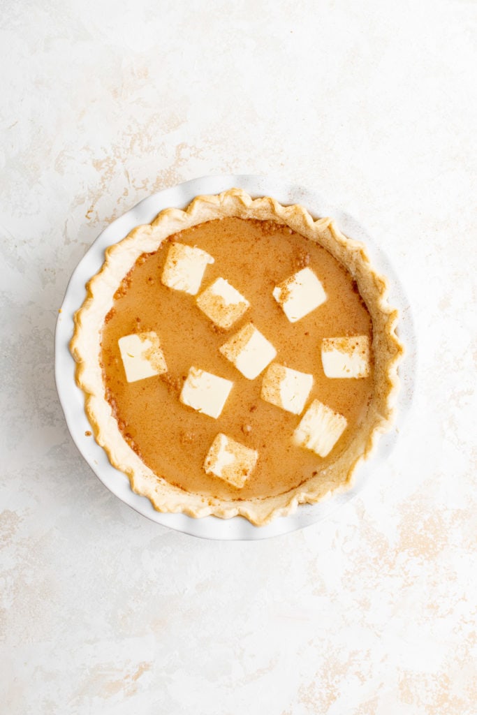 Top down view of butter slices on unbaked pie.