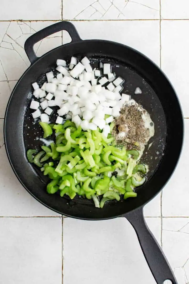 Southern Cornbread Dressing Recipe Top down view of onions, celery and spices in a pan.