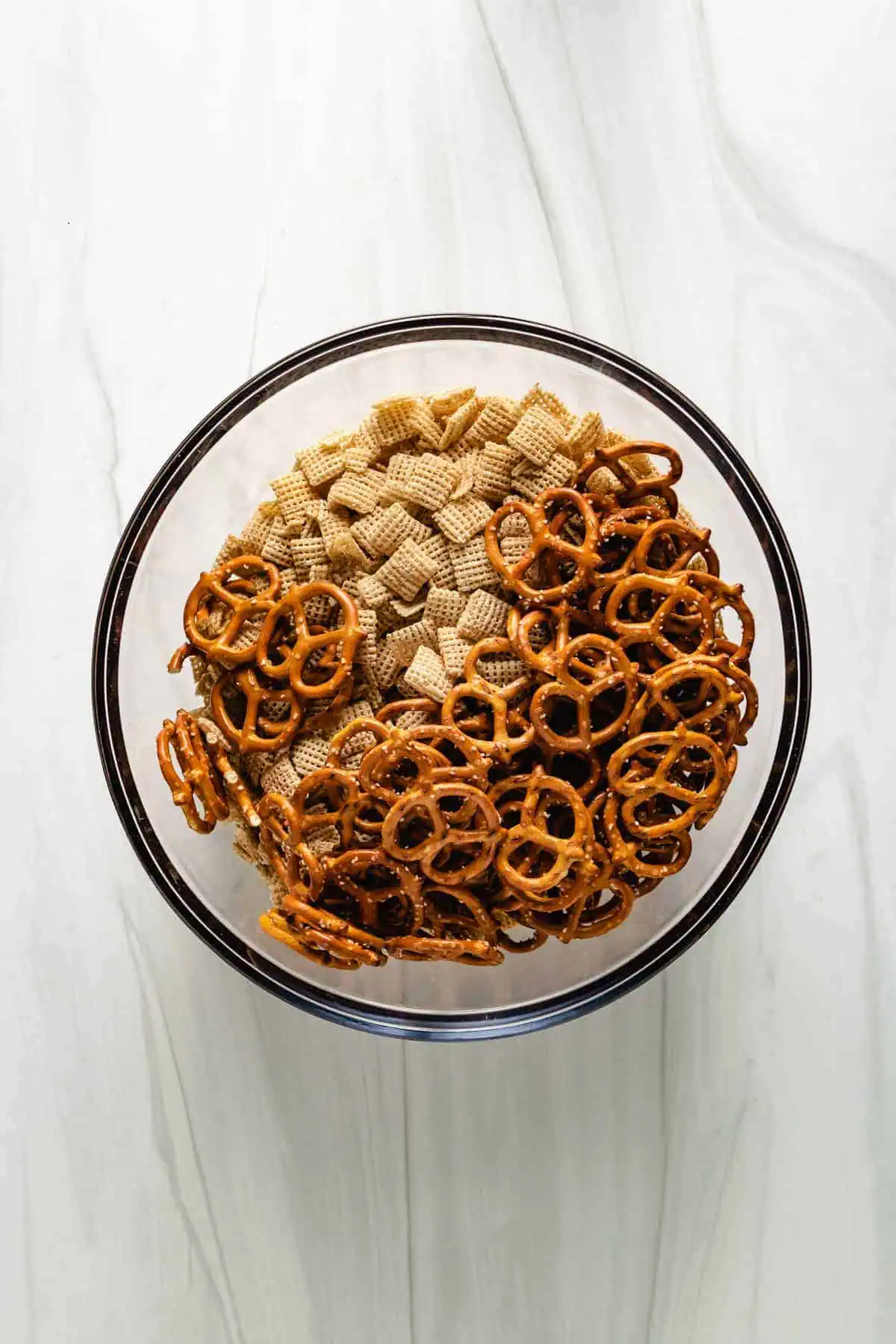 Top down view cereal and pretzels in a bowl.