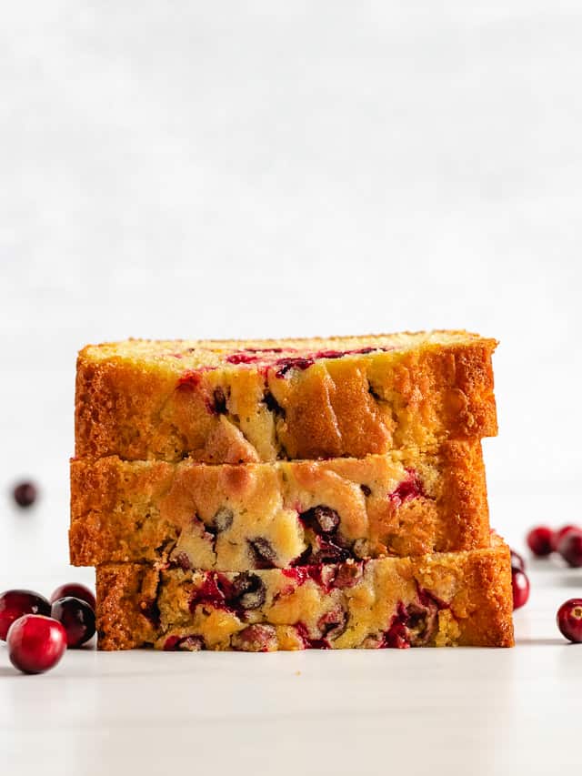 Stack of quick cranberry orange bread with fresh cranberries.