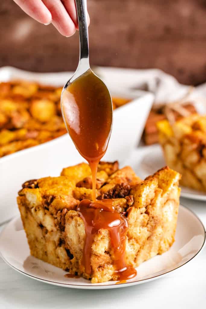 Spoon drizzling caramel sauce on bread pudding.