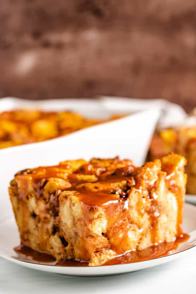 Slice of pumpkin bread pudding topped with caramel sauce.